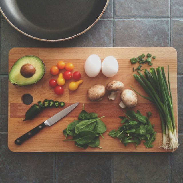 A wooden cutting board prepped with fresh vegetables in a new kitchen